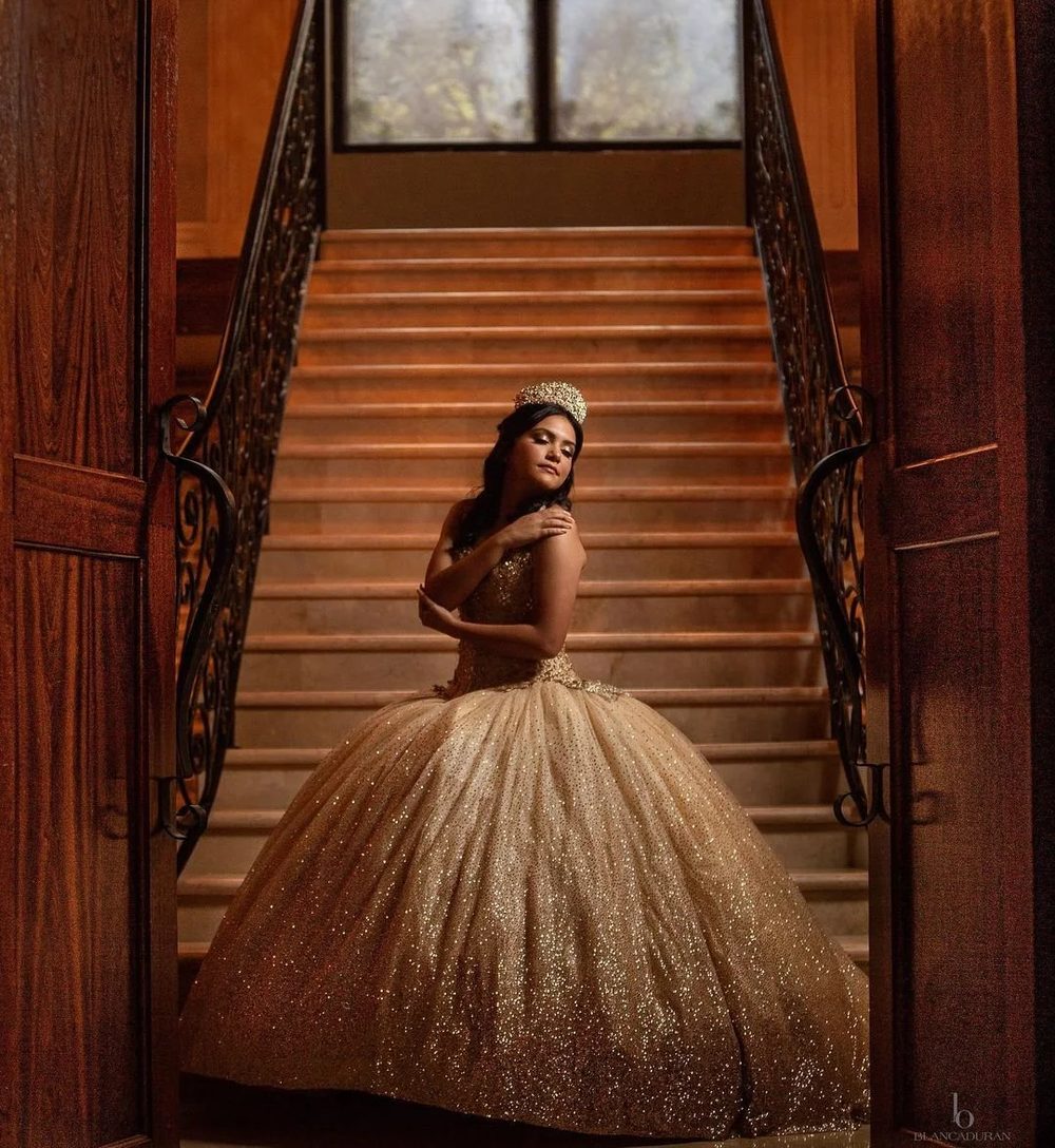 Quinceañera in a gold gown on the grand staircase at The Bell Tower on 34th, Houston, TX.