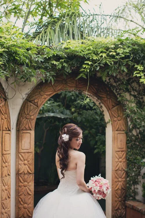 Bride with bouquet at the courtyard garden arch at The Bell Tower on 34th, Houston, TX.